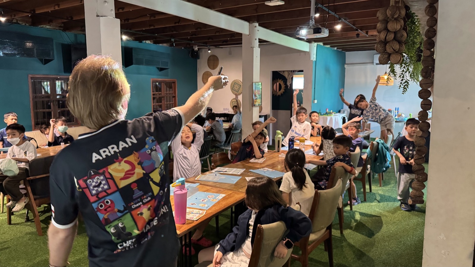 Young children raising hands enthusiastically during Chess Story Time