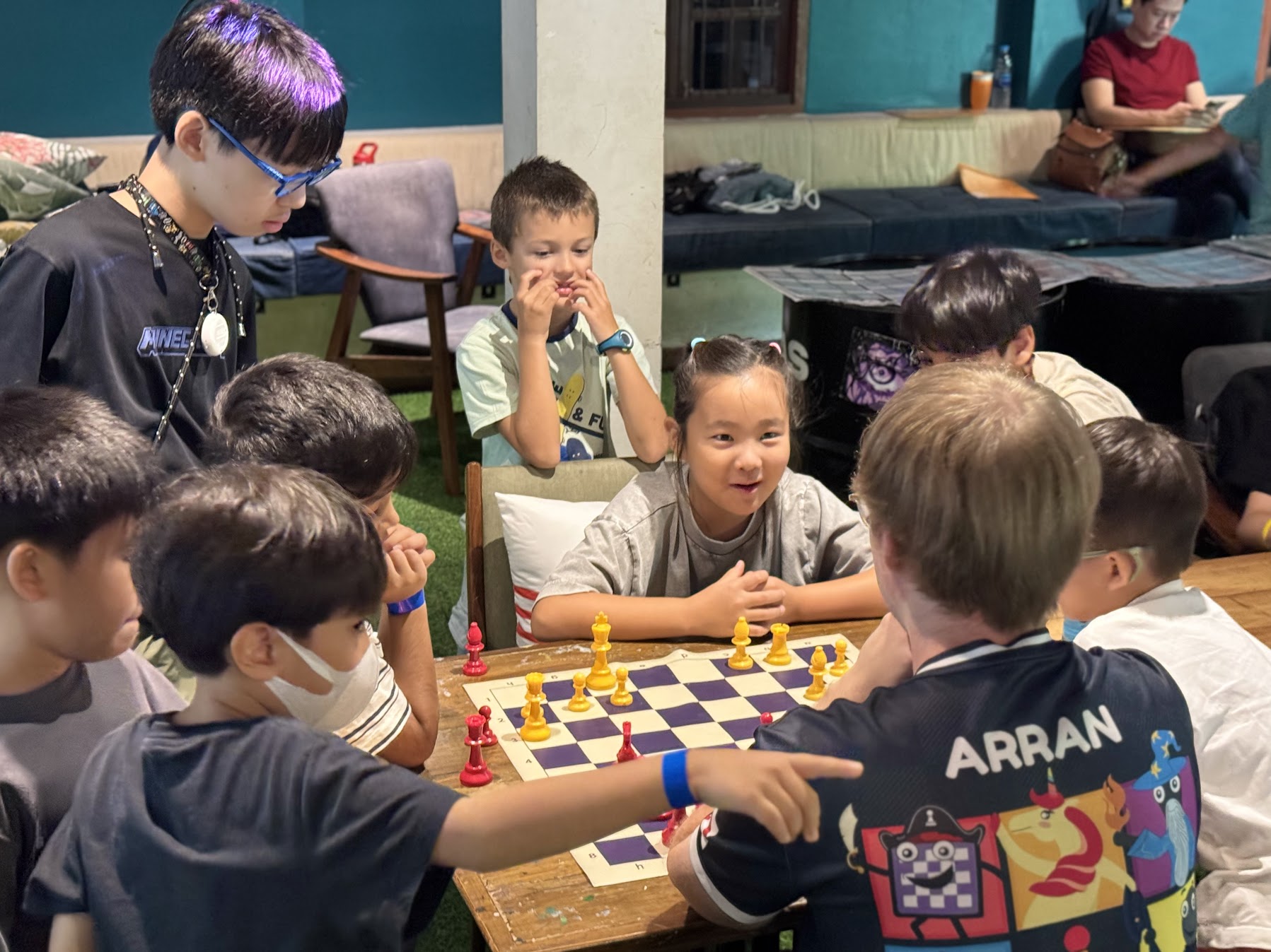 Coach and kids gathered around a team chess board