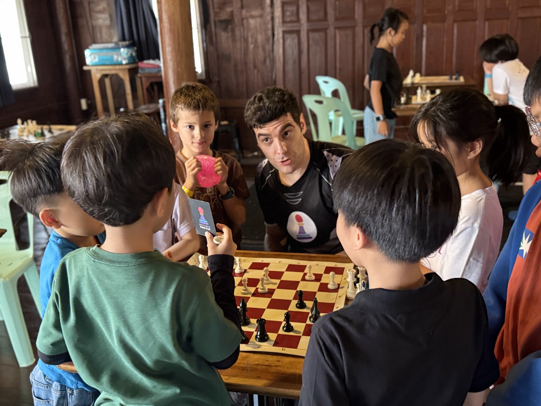 Coach chatting with kids around the chess board